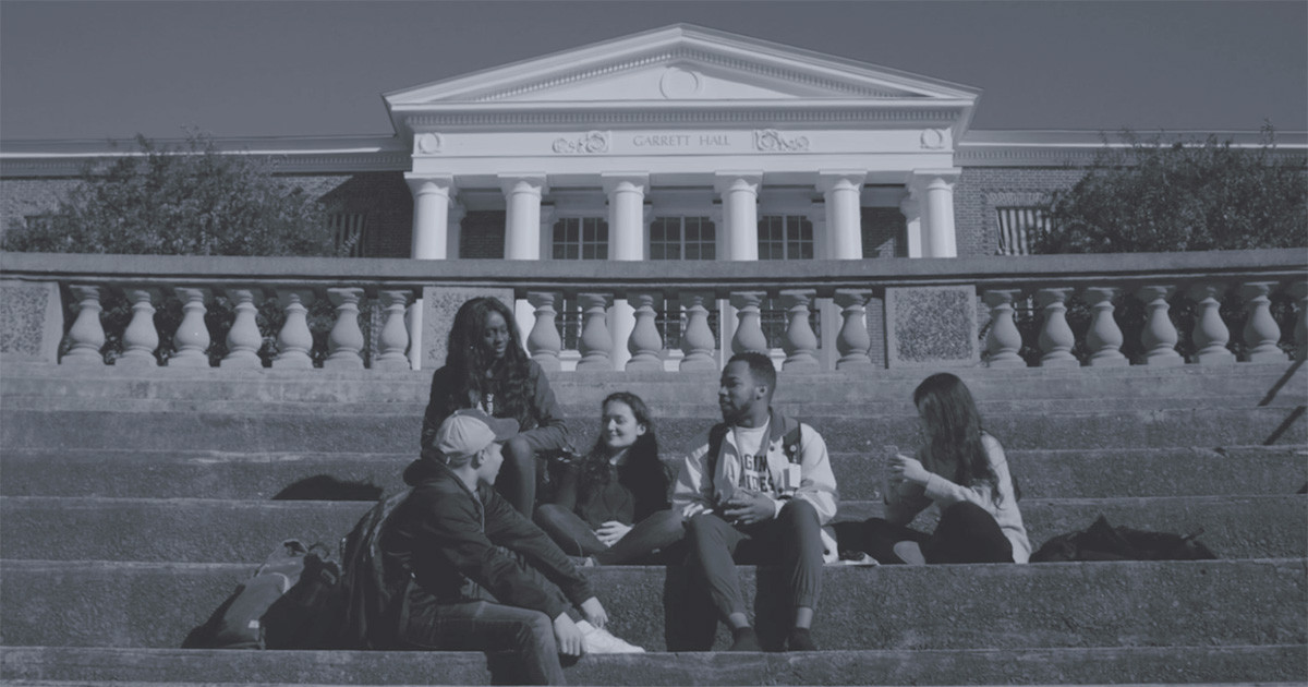 A diverse group of students talk while sitting on the steps outside of Garrett Hall.